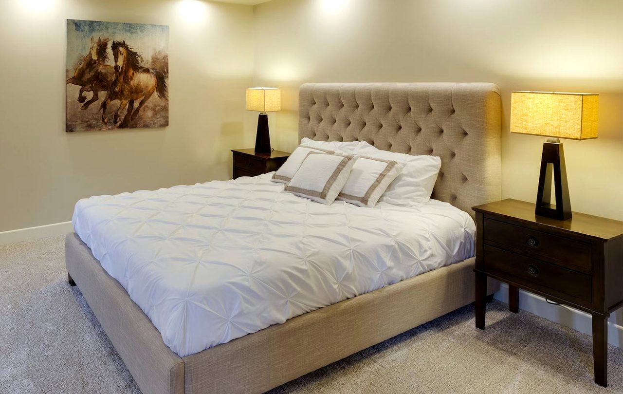 A double room with a buttoned headboard, lamps and a framed picture of horses